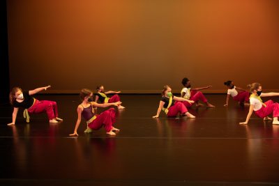 A large group of young dancers performing a modern dance on a stage.