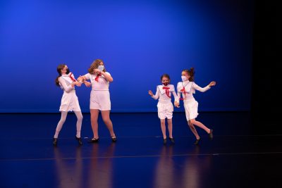 Four young dancers in sailor-themed costumes performing on a stage.