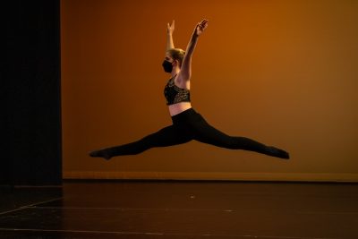 A Teen Performance Company dancer mid-leap across a stage.