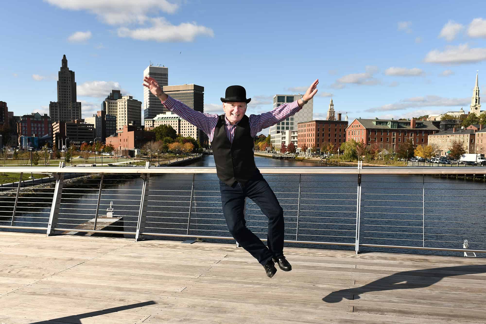 Kevin Doyle jumping on a boardwalk with a skyline behind him.
