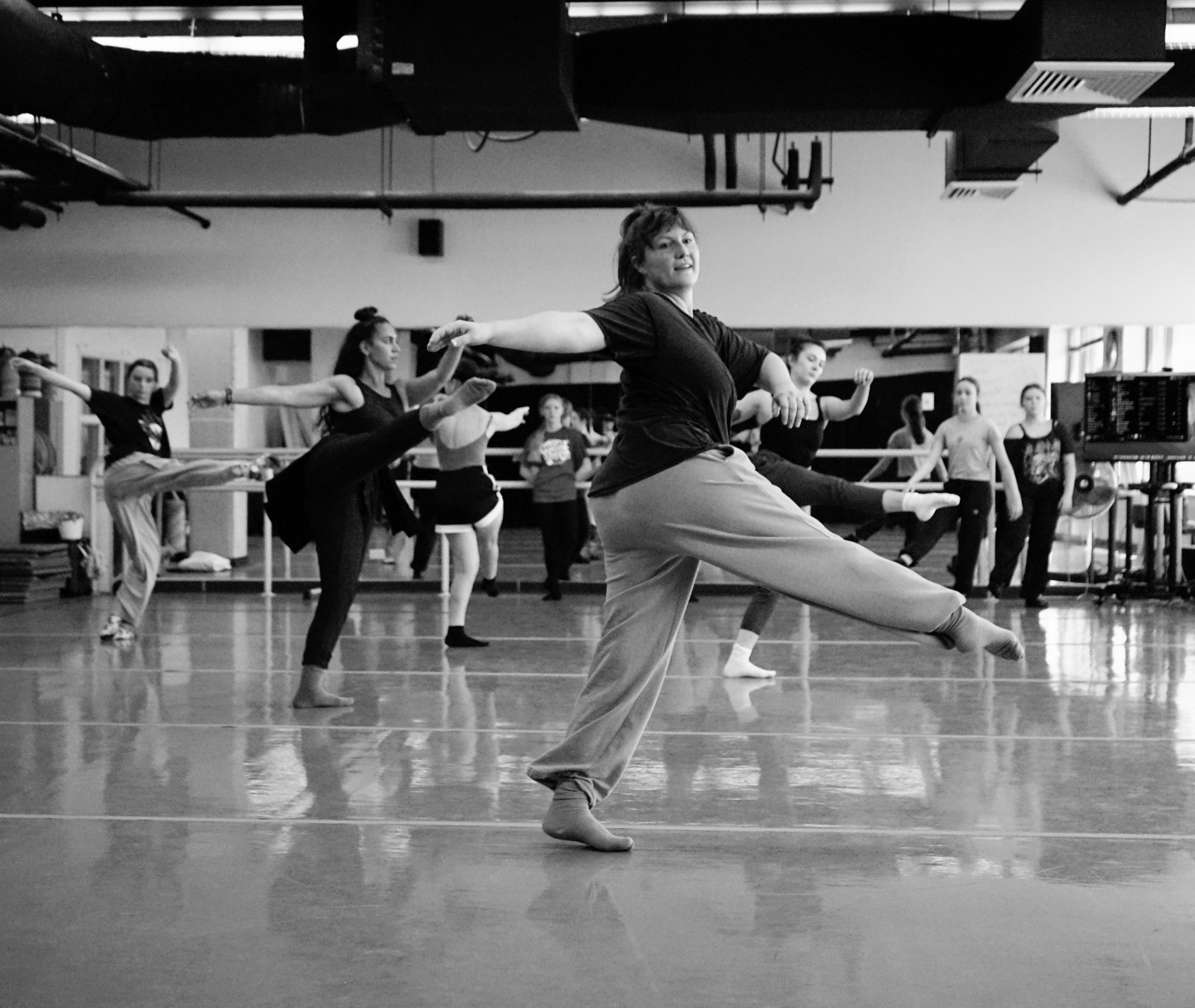 A class of dancers swings their leg
