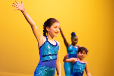 3 tween dancers in bright blue costumes strike a jazzy pose during Dance Project's Spring showcase.