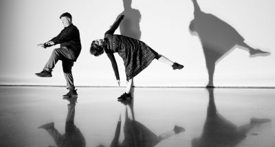 Choreographers Chris Yon and Taryn Griggs performing a duet in a brightly lit performance space.