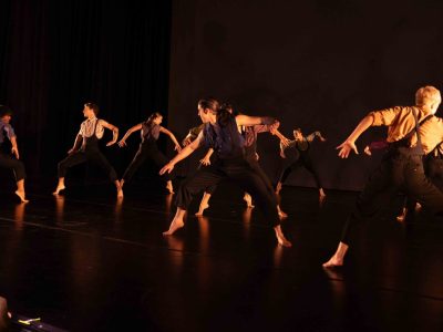 A group of dancers perform Stewart Owen's choreography, facing off against each other with their arms and legs tensed aggressively.