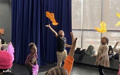 Several first grade students joyfully toss colorful scarves into the air during dance class at Peck Elementary.