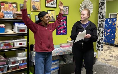 Two young adults stand in the craft room at Reconsidered Goods working on a dance and poetry collaboration.