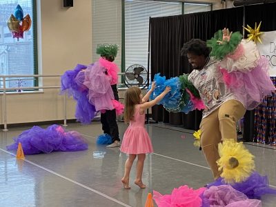 Two Dance Project instructors stand in the dance studio, covered in colorful tutus during the Birthday Bash Tutu Challenge