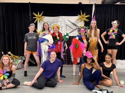 A group of teen and adult dancers, some in wacky costumes, pose in Dance Project's studio during the Birthday Bash.